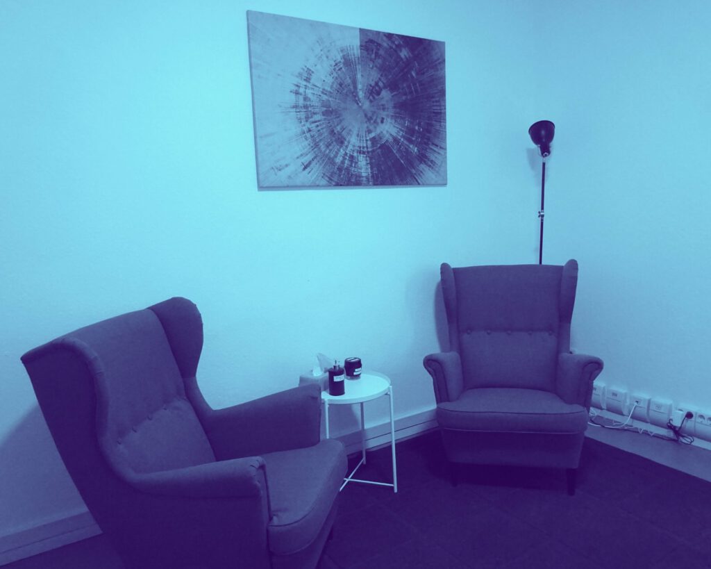 Ausschnitt aus dem Beratungsraum: Zwei gemütliche Sessel. Darüber hängt ein absraktes Bild.
